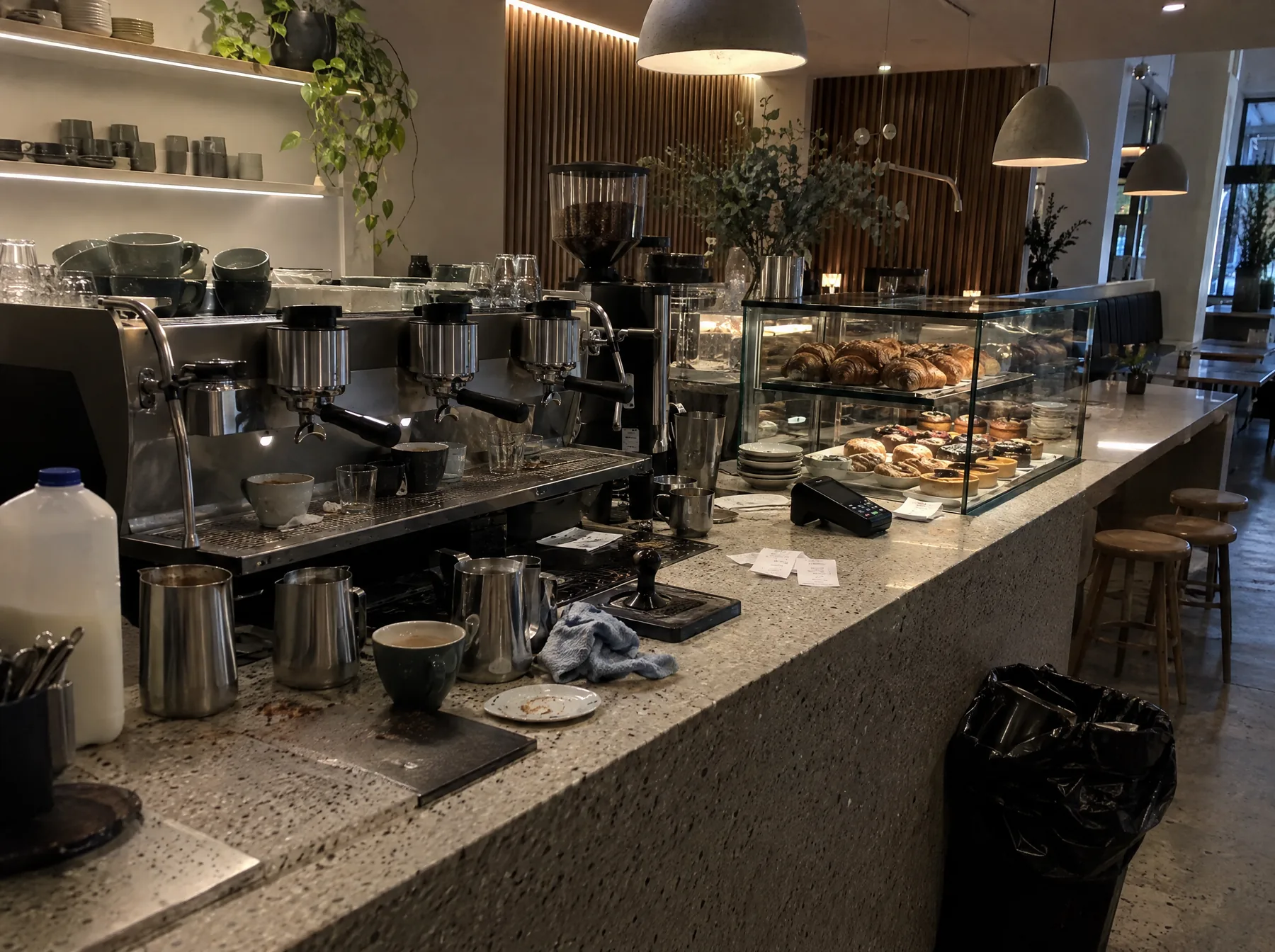Before: a terrazzo cafe counter cluttered with milk bottles, used cups and a bin bag