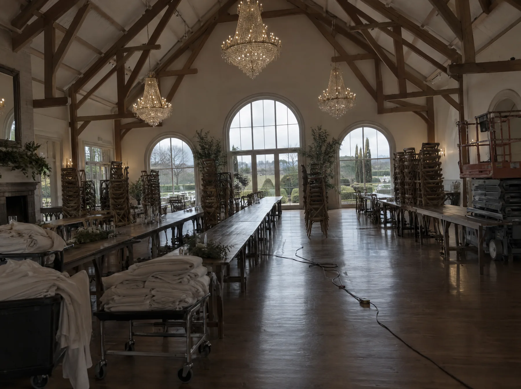 Before: a chandeliered barn venue with stacked chairs, linen trolleys and a scissor lift