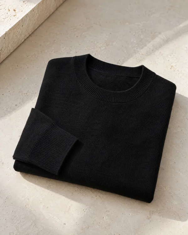 A black merino crew jumper folded on limestone