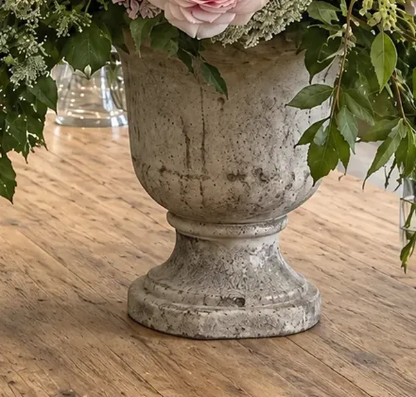 A stone urn with peonies and roses on a timber bench